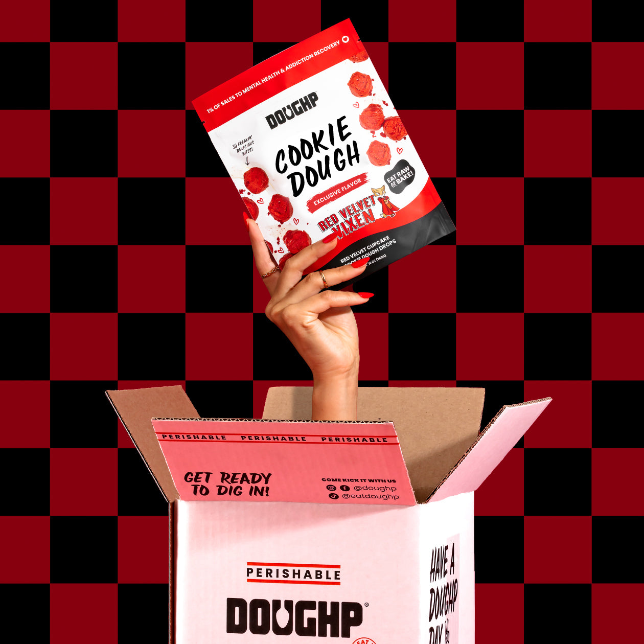 Cookie dough box from Doughp with hand coming out from it holding a Red Velvet flavored pouch of Doughp cookie dough drops