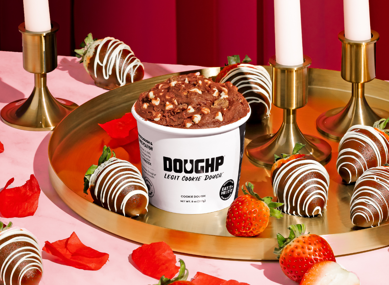 hand reaching into plate full of red velvet cookie dough bites with cupcake nearby and Doughp's cookie dough drops bag behind