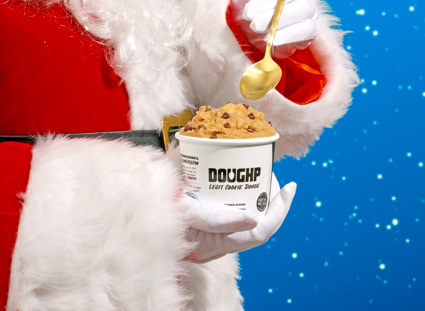 Santa Claus taking a spoon of chocolate chip cookie dough from Doughp on a festive blue background